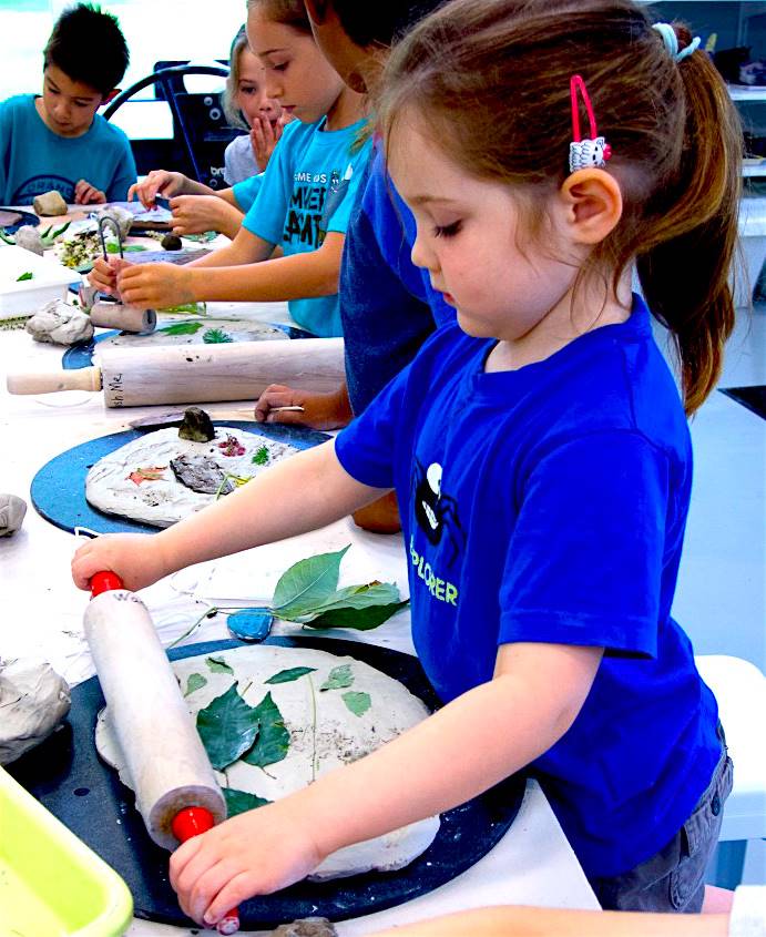 Child creating art with rolled clay