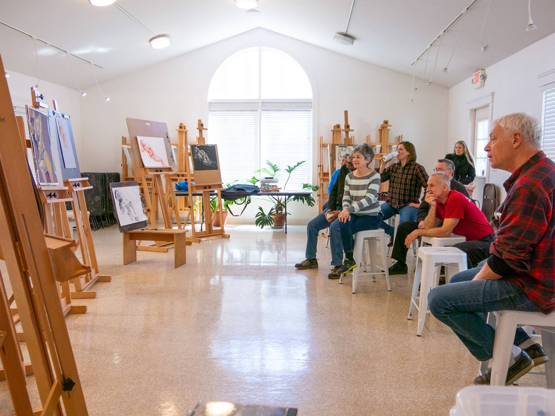 Art participants studying paintings on easels