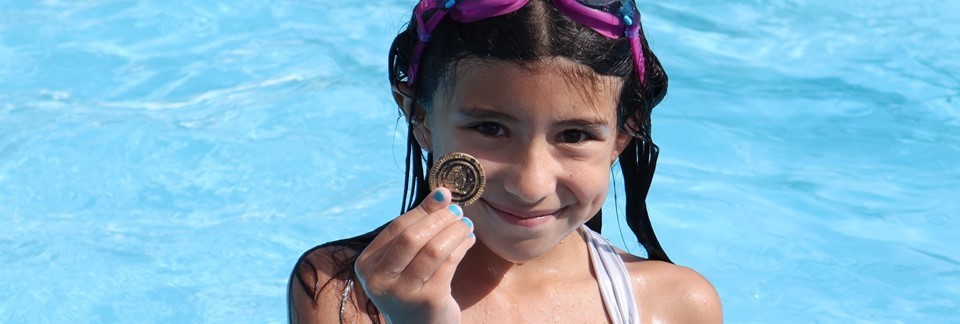 Girl holding treasure hunt coin found in the pool during special event