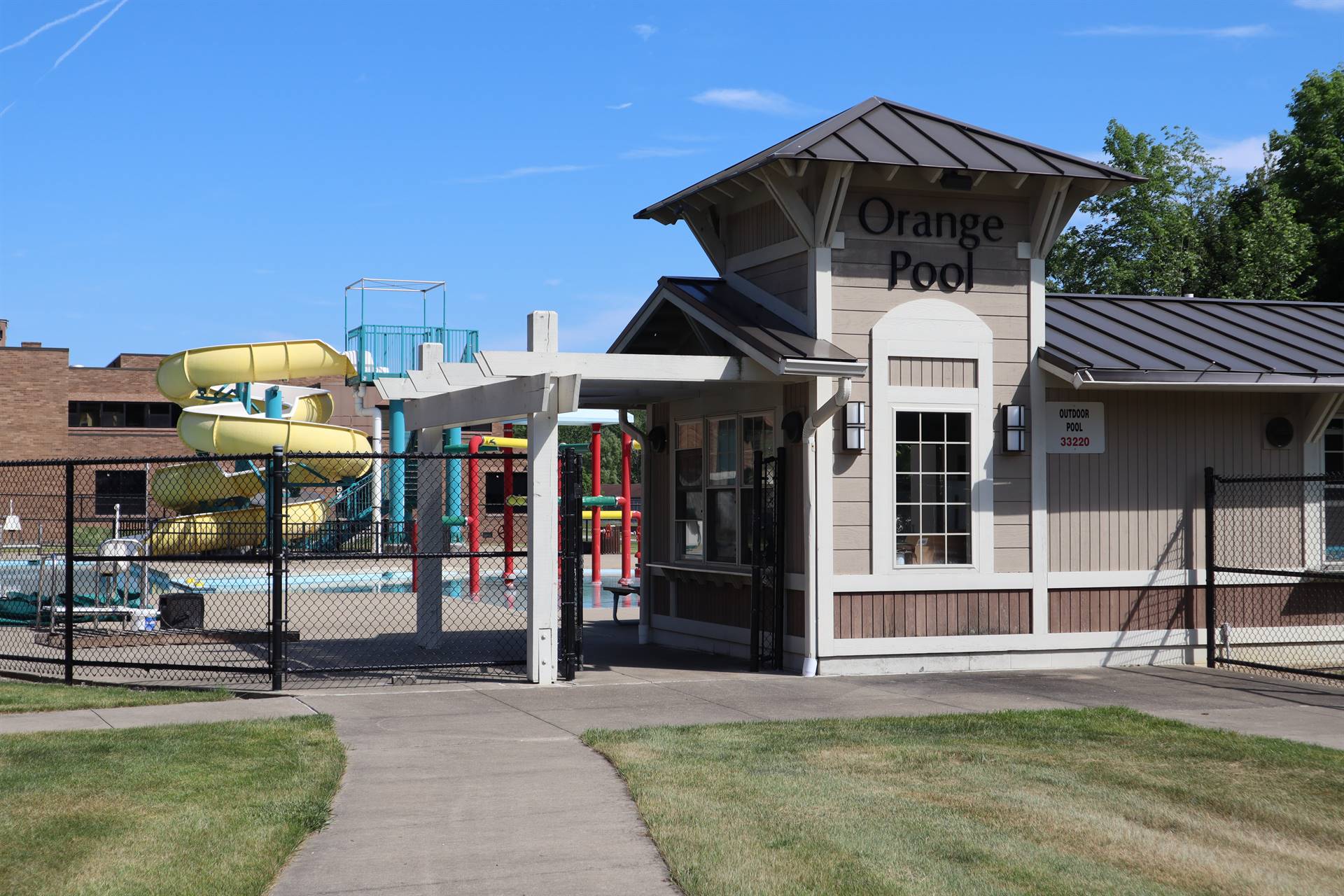 Outdoor pool entrance with yellow slide in the background 