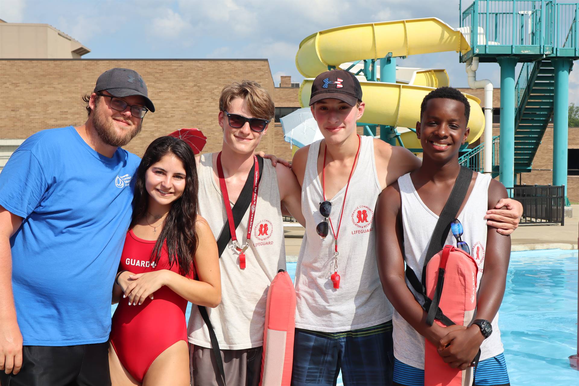 Five lifeguards wearing red whistles and lifeguard uniforms 