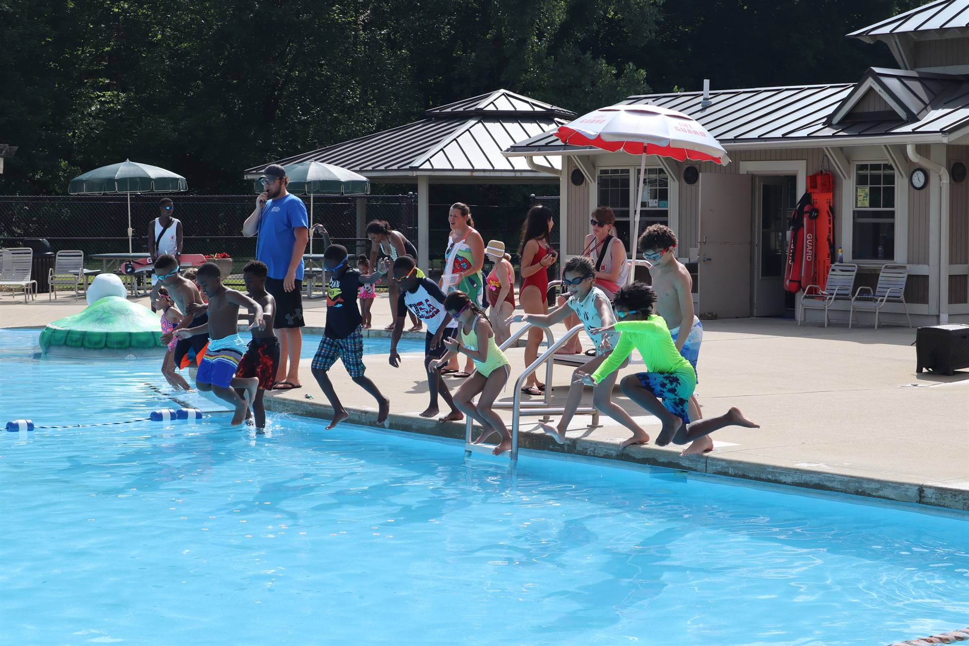 Children jumping in to the outdoor pool 
